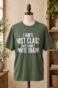 Military-green graphic tee displayed on a mannequin in a rustic boutique setting